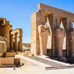 Explore the ancient ruins of Medinet Habu Temple in Egypt, showcasing impressive stone statues and columns.