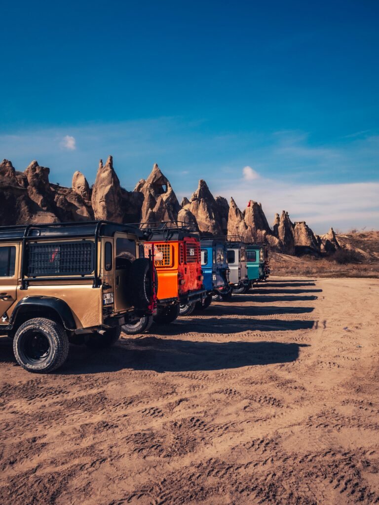 Parked offroad vehicles in the rocky landscape of Ürgüp, showcasing unique geological formations.